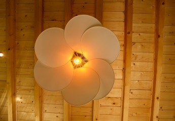 Lampada da soffitto moderna a forma di petali accesa e vista dal basso al Wellnest di Camping Vinkenhof.