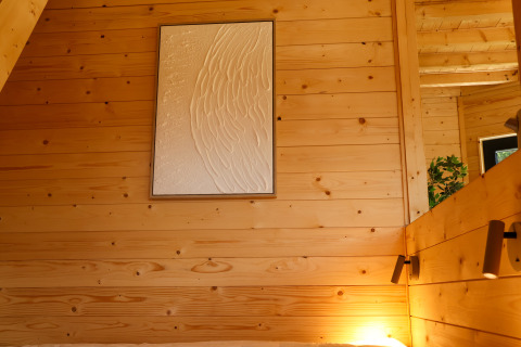 Interior de cabaña de madera en Wellnest, Camping Vinkenhof, Países Bajos, con arte mural y luz acogedora.