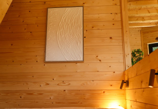 Interior de cabaña de madera en Wellnest, Camping Vinkenhof, Países Bajos, con arte mural y luz acogedora.
