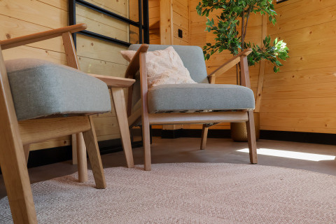 Sillones cómodos, mesa auxiliar y planta en una cabaña de madera en Wellnest, Camping Vinkenhof, Países Bajos.