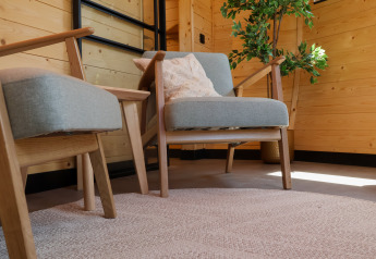 Poltrone comode e tavolino in una lodge in legno presso Wellnest, Camping Vinkenhof, Paesi Bassi.