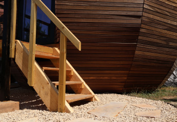 Scala esterna in legno e facciata moderna del lodge Wellnest al Camping Vinkenhof, Paesi Bassi.
