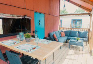Espace repas et salon extérieur à Wander Lodge du Holiday park De Boshoek aux Pays-Bas, porte bleue.