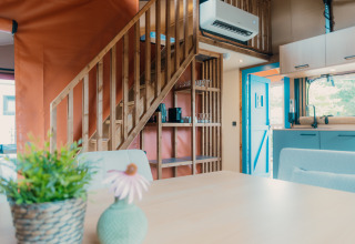 Interior de una acogedora cabaña con escalera de madera y cocina abierta en Wander Lodge, De Boshoek, Países Bajos.