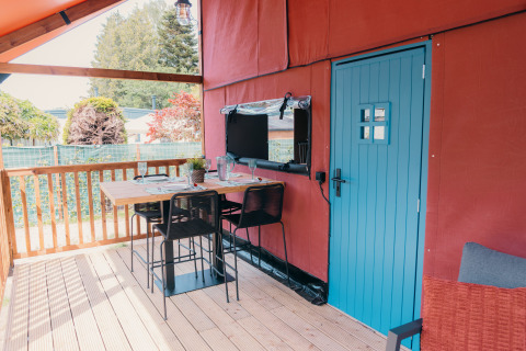 Udendørs spiseområde på terrassen af Wander Lodge med blå dør og hyggelig borddækning.