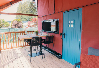 Zona pranzo all’aperto sul terrazzo di Wander Lodge, con porta blu e tavolo apparecchiato accogliente.