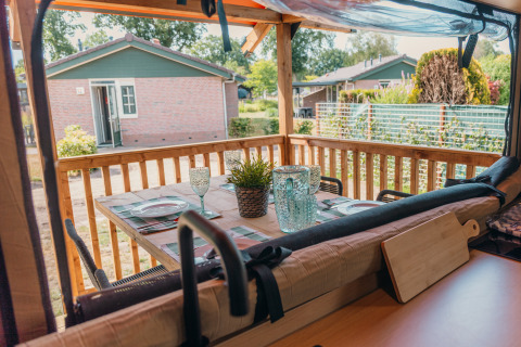 Vista dalla Wander Lodge all'Holiday Park De Boshoek, tavolo apparecchiato su veranda in legno, Paesi Bassi.