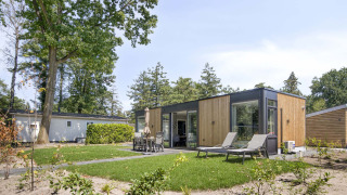 Lodge moderno presso Veluwehoeve con lettini da sole e area pranzo esterna in giardino verde.