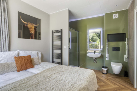 Modernes Zimmer in der Veluwehoeve im Bospark Ede mit Bett, offenem Bad und Wandbild eines Stiers.