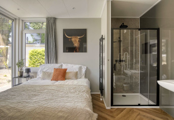 Lichte slaapkamer in Veluwehoeve, Bospark Ede, met tweepersoonsbed, moderne douche en grote ramen.