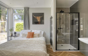 Lichte slaapkamer in Veluwehoeve, Bospark Ede, met tweepersoonsbed, moderne douche en grote ramen.