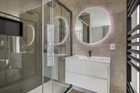 Baño moderno en Veluwehoeve en Bospark Ede, Países Bajos, con espejo redondo y cabina de ducha.