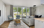 Salon moderne du lodge Veluwehoeve à Bospark Ede, Pays-Bas, avec de grandes fenêtres et un décor élégant.