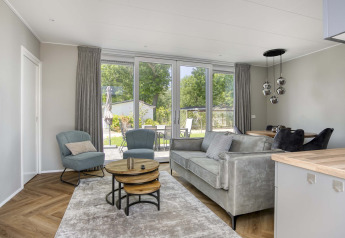 Soggiorno moderno nel lodge Veluwehoeve a Bospark Ede, Paesi Bassi, con ampie finestre e arredi eleganti.