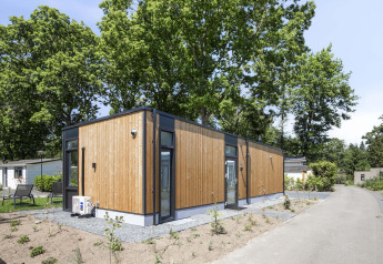 Lodge moderno rivestito in legno al Bospark Ede nei Paesi Bassi, circondato da alberi e sentieri tranquilli.