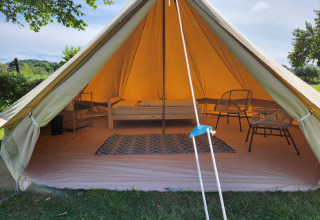 Entrada de la tienda safari Belltent en Camp Diekirch, Luxemburgo, con cama, alfombra y sillas dentro.