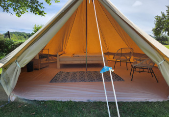 Ingang van de Belltent safaritent op Camp Diekirch in Luxemburg, met bed, tapijt en stoelen binnenin.