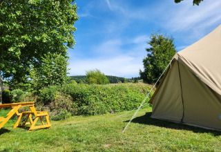 Safari-belltent en gele picknickbank op Camp Diekirch in Luxemburg, in een groene, natuurlijke omgeving.