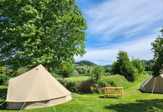 Tienda safari Belltent en Camp Diekirch, Luxemburgo, en un día soleado con campos y árboles verdes.