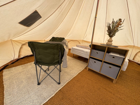 Interno della tenda Tipi al Rosenvold Strand Camping con sedia, letto, scaffale e fiori secchi.