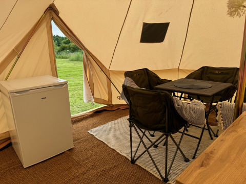 Innenraum eines Tipi-Zeltes bei Rosenvold Strand Camping in Dänemark mit Stühlen, Tisch und Kühlschrank.