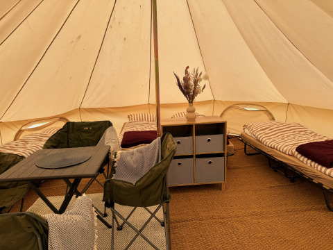 Indretning af Tipi telt med senge, stole og borde hos Rosenvold Strand Camping i Danmark.