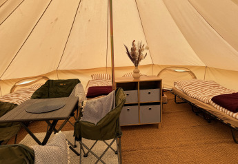 Interno di una tenda tipi con letti e sedie al Rosenvold Strand Camping in Danimarca.