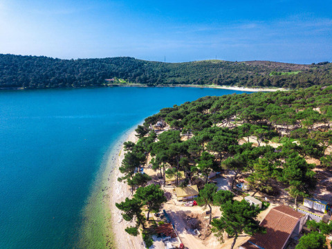 Aerial view of Camping Arena One 99 Glamping in Istria, Croatia, with pine trees, beach, and blue sea.