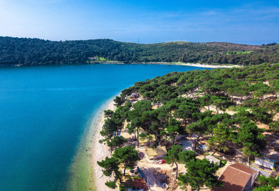 Vista aérea de Camping Arena One 99 Glamping en Istria, Croacia, con playa, bosques y mar azul intenso.