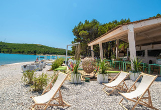 Relaxing beach area at Camping Arena One 99 Glamping in Istria, Croatia, with deck chairs and a beach bar.