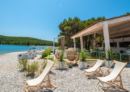 Strandgedeelte van Camping Arena One 99 Glamping in Istrië, Kroatië met ligstoelen en strandbar.