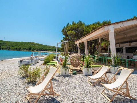 Relaxing beach area at Camping Arena One 99 Glamping in Istria, Croatia, with deck chairs and a beach bar.