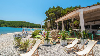 Afslappende strandområde ved Camping Arena One 99 Glamping i Istrien, Kroatien med stole og strandbar.