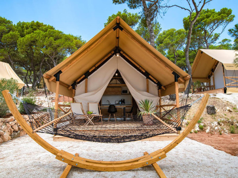 Tenda safari con due camere da letto al Camping Arena One 99 Glamping in Croazia, con amaca e tavolino esterno.