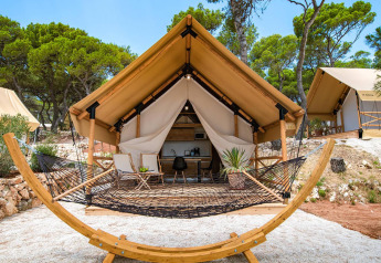 Tenda safari con due camere da letto al Camping Arena One 99 Glamping in Croazia, con amaca e tavolino esterno.
