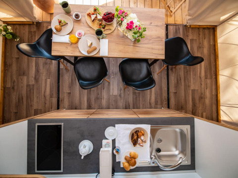 Bovenaanzicht van eettafel en kitchenette in tweeslaapkamer safaritent bij Camping Arena One 99 Glamping, Kroatië.
