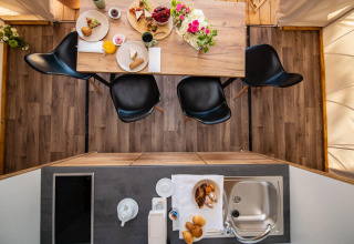 Top view of dining table and kitchenette inside two-bedroom safari tent at Camping Arena One 99 Glamping, Croatia.