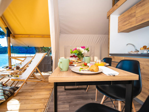 Colazione su tavolo in legno dentro una tenda glamping al Camping Arena One 99 Glamping in Istria, Croazia.