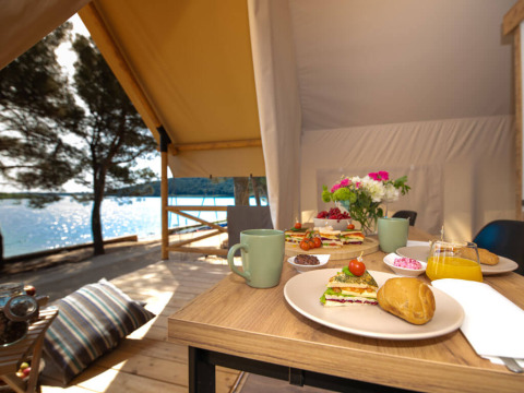 Petit-déjeuner en glamping sur une terrasse face à l’eau au Camping Arena One 99 Glamping en Istrie, Croatie.