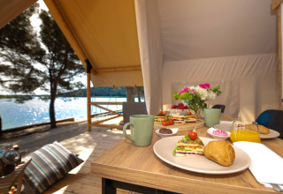 Petit-déjeuner en glamping sur une terrasse face à l’eau au Camping Arena One 99 Glamping en Istrie, Croatie.