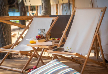 Due sedie a sdraio e un tavolino con snack e succo su una terrazza di una tenda safari in Croazia.