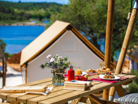 Petit-déjeuner en plein air sur une table en bois avec vue sur la mer au Camping Arena One 99 Glamping en Istrie, Croatie.