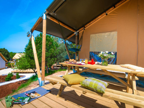 Gemütliche Terrasse mit Holztisch an einem Zwei-Schlafzimmer-Safarizelt bei Arena One 99 Glamping, Kroatien.
