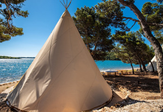 Large tipi near the lakeside surrounded by trees and picnic tables at Camping Arena One 99 Glamping, Istria, Croatia