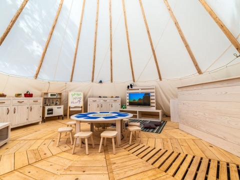 Zona de juegos infantil interior con muebles de madera, mesas y taburetes en tienda en Arena One 99 Glamping, Istria.