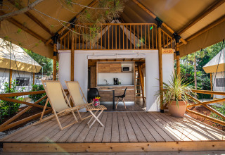Glamping tent at Camping Arena One 99 in Istria, Croatia, featuring a wooden deck, lounge chairs and kitchenette.