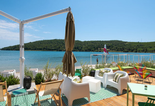 Outdoor lounge area with modern seating overlooking the bay at Camping Arena One 99 Glamping in Istria, Croatia.