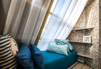 Angolo accogliente in tenda safari con divano blu, cuscini a righe, mensole e insegna decorativa.
