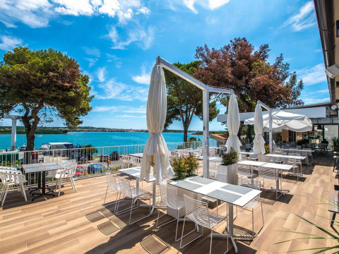 Terrazza all'aperto con tavoli da pranzo e vista mare al Camping Arena One 99 Glamping in Istria, Croazia.