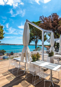 Udendørs terrasse med spiseborde og udsigt over havet og træer på Camping Arena One 99 Glamping i Istrien, Kroatien.